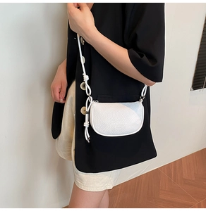 Détail du sac selle blanc en cuir grainé avec bandoulière nouée sur une épaule
