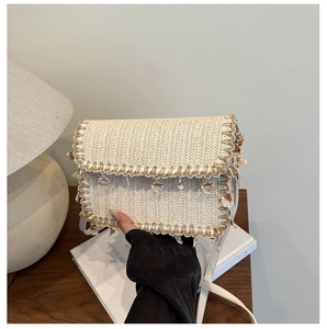 Dettaglio borsa boho in paglia intrecciata con vere conchiglie e tracolla bianca elegante