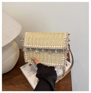 Dettaglio borsa a tracolla in paglia intrecciata con nappe beige e decorazioni di conchiglie