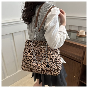 Detail of leopard print tote bag with silver chain and leather logo tag on a shoulder strap