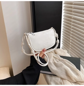 Détail du sac bandoulière en cuir blanc grainé avec bandoulière nouée et zip argenté