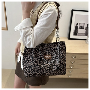 Detail of leopard print tote bag with brown leather label and metal chain strap