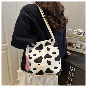 Detail van de bucket tote met koeienprint, roze kwastje en mode lederen label