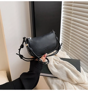 Détail du sac à main en cuir grainé noir avec bandoulière à nœud et zip argenté