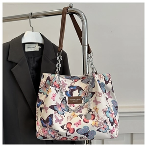 Detail of white tote bag with colorful butterfly prints and silver chain accessory