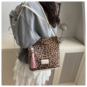 Luipaardprint shopper met roze kwastje gedragen door een model in een natuurlijke setting