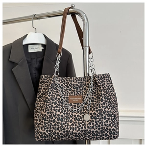 Detail of leopard print canvas tote bag featuring metal chain and leather shoulder strap