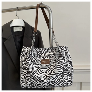 Detail of zebra print tote bag featuring leather straps and silver metal chain link detail