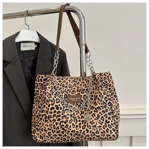 Detail of leopard print tote bag featuring brown leather strap and silver chain handle