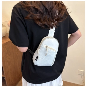 Bolso cruzado de nailon blanco con correa negra ajustable usado en la espalda del modelo