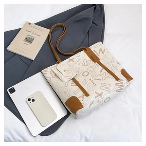 Détail d'un grand cabas beige avec imprimé de lettres et une pochette assortie