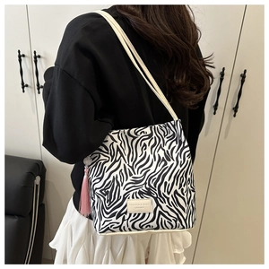 Detail van de zebra shopper tas met roze kwastje en smalle bandjes op de schouder