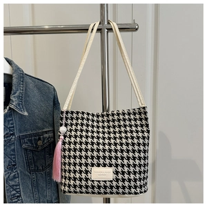 Detail van de houndstooth shopper met wit leren label en roze kwastje hanger