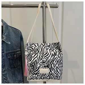 Detail van de zebra tote tas met roze kwastje en leren label aan een kledinghanger