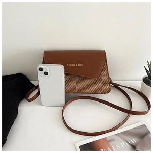 Detailed view of brown woven texture crossbody bag with leather flap and smartphone for scale