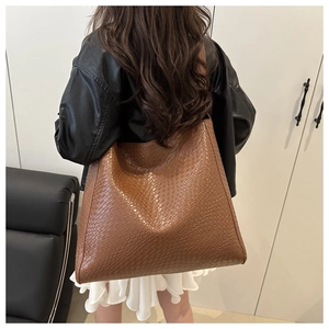 Gros plan sur la texture tressée marron d'un grand cabas porté à l'épaule d'un mannequin