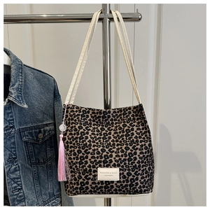 Detail van de bucket bag met luipaardprint, roze franje kwastje en modieus lederen label