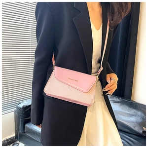 Close-up of pink woven and leather crossbody bag worn with a black blazer