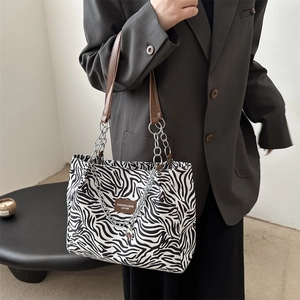 Chic zebra print tote bag with brown leather handles and silver chain detail