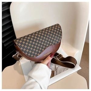 Close-up of vintage brown saddle bag with floral patterns and a wide fabric strap