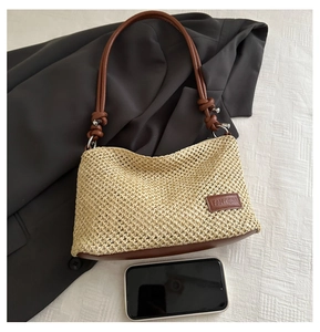 Détail du sac à bandoulière en paille tissée avec sangles en cuir et patch logo