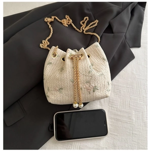 Détail d'un sac seau tissé beige avec broderie florale et cordons ornés de perles
