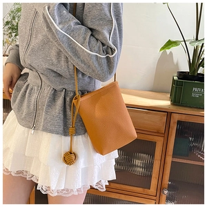 Vue détaillée du sac à téléphone orange avec cuir grainé litchi et bandoulière à nœuds