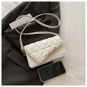 Detail of white quilted crossbody bag with golden hardware on a black blazer
