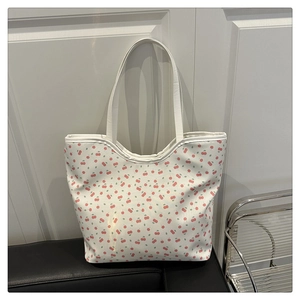 Détail du motif cerise sur le sac fourre-tout en toile posé sur un siège noir