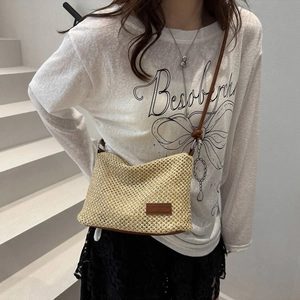 Beige woven crossbody bag with brown leather strap and logo patch for casual summer style