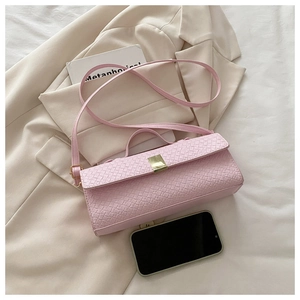 Close-up of pink woven baguette bag with gold buckle on white bedding