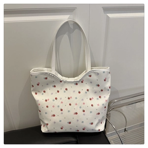 Détail d'un sac cabas en toile blanche avec motifs de fraises et fleurs