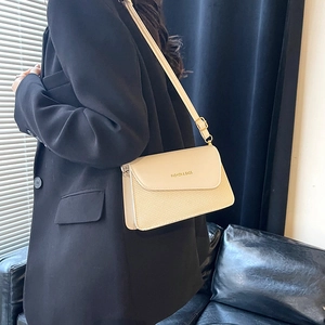 Elegant beige woven crossbody bag with leather flap and adjustable strap on a model