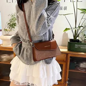 Brown leather crossbody bag with woven texture worn by model in a casual home setting
