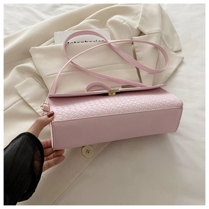 Close-up of pink crossbody bag with woven texture lid and golden metallic buckle detail