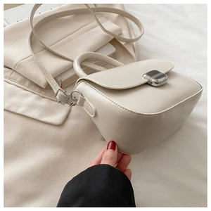 Detail of cream white PU leather handbag with silver metal buckle and adjustable strap