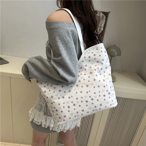 Sac fourre-tout en toile à fleurs mauves porté par un mannequin dans un cadre minimaliste