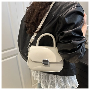Rear view of cream leather shoulder bag with silver clasp styled on a model