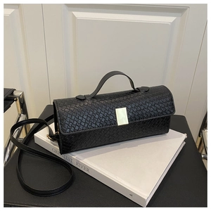 Detailed close-up of a black woven leather handbag with a sleek golden metal clasp