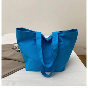 Detail of bright blue canvas tote bag with wide shoulder straps on a clean tabletop