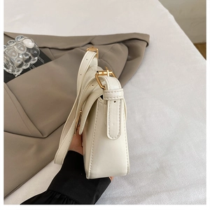 Detail view of white leather shoulder bag with adjustable strap and gold metal hardware