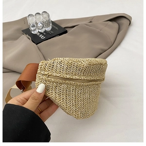 Détail macro du sac de poitrine en paille tissée avec motif en V et fermeture éclair
