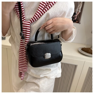 Classic black leather crossbody bag with silver buckle worn by a model in casual setting