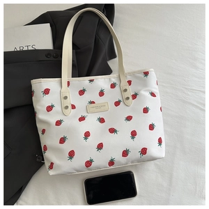 Detail of white strawberry print tote bag with leather handles and fashion logo patch