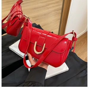 Close-up of red patent leather handbag featuring a stylish gold U-shaped metal buckle