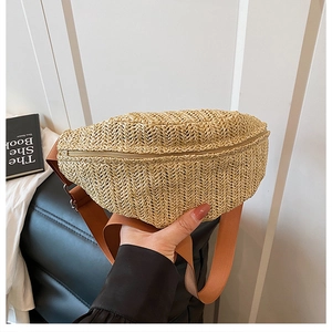 Gros plan d'un sac banane en paille tressée beige avec fermeture éclair dorée