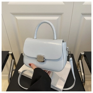 Detail of light blue crossbody bag with silver square lock and leather texture