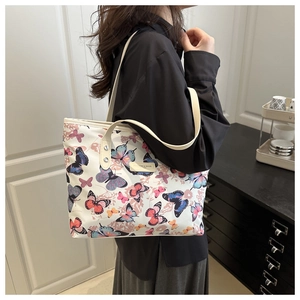 Detail view of large white tote bag with colorful butterfly prints on model's shoulder