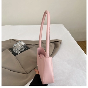 Close-up of a minimalist light pink faux leather underarm bag with smooth finish