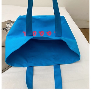 Close-up of sky blue canvas tote bag with pink artistic lettering and wide handle